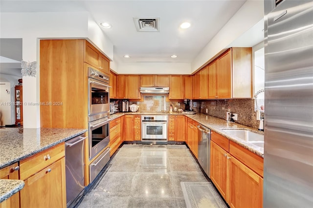 kitchen with light stone counters, stainless steel appliances, and tasteful backsplash