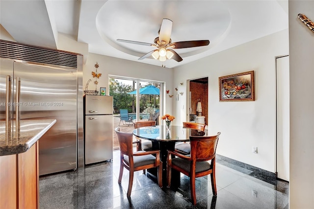 dining room with ceiling fan and a tray ceiling