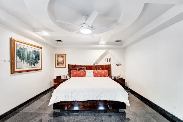 carpeted bedroom with ceiling fan and a tray ceiling