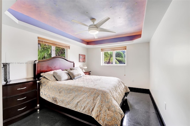 bedroom with ceiling fan and a raised ceiling