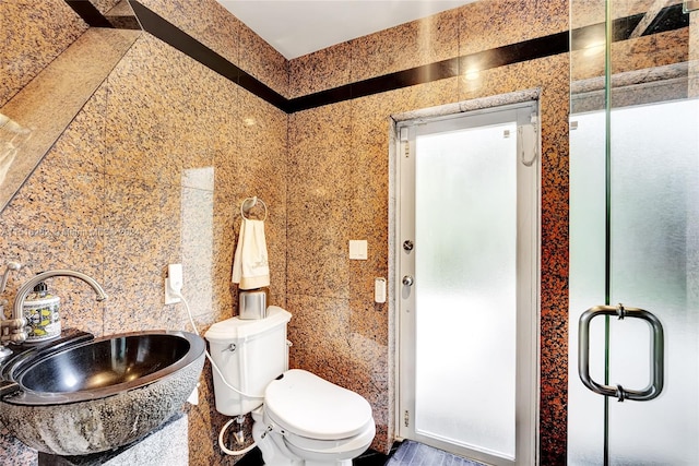 bathroom featuring toilet, an enclosed shower, sink, and tile walls