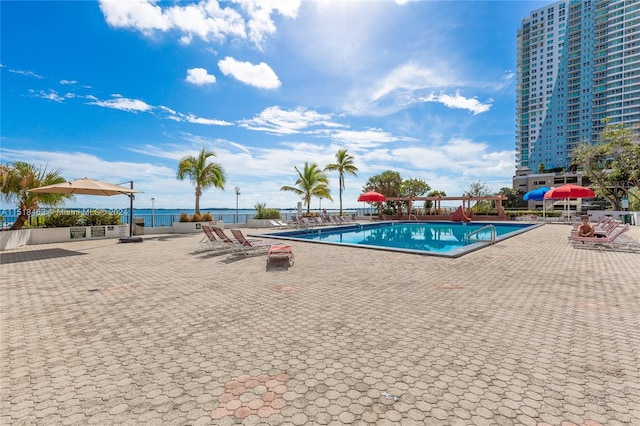 view of pool with a water view and a patio