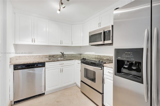 kitchen with light stone countertops, sink, white cabinets, and appliances with stainless steel finishes