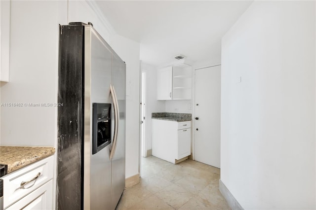 kitchen featuring white cabinets, stainless steel fridge, and dark stone countertops