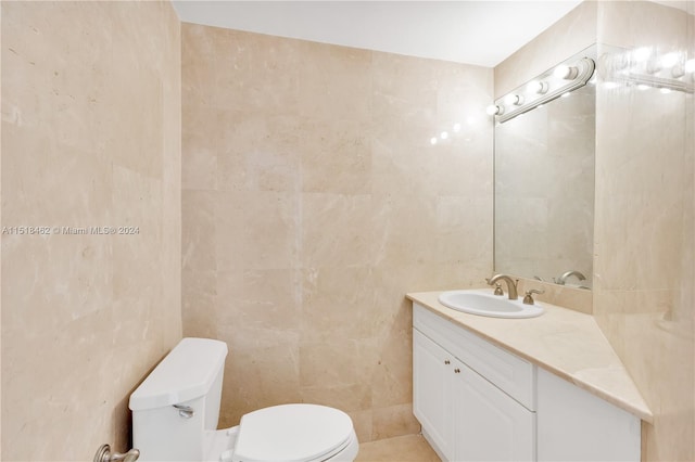 bathroom featuring vanity, toilet, and tile walls