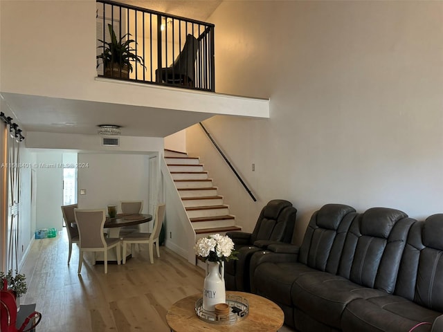 living room featuring a barn door, light hardwood / wood-style floors, and a high ceiling