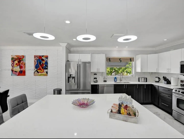 kitchen with pendant lighting, tasteful backsplash, appliances with stainless steel finishes, white cabinetry, and sink