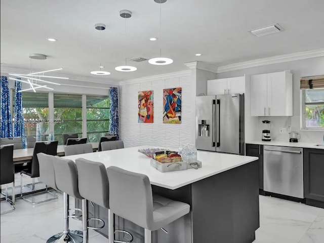 kitchen featuring light tile floors, a kitchen breakfast bar, hanging light fixtures, appliances with stainless steel finishes, and white cabinetry