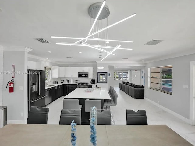 kitchen with pendant lighting, ornamental molding, black appliances, white cabinetry, and a center island