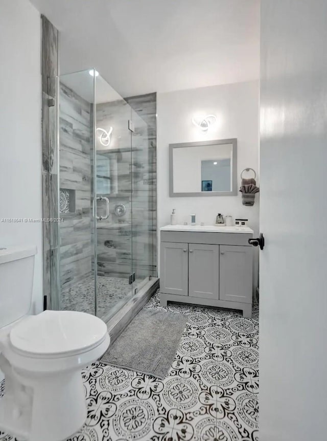 bathroom with walk in shower, toilet, tile floors, and vanity with extensive cabinet space