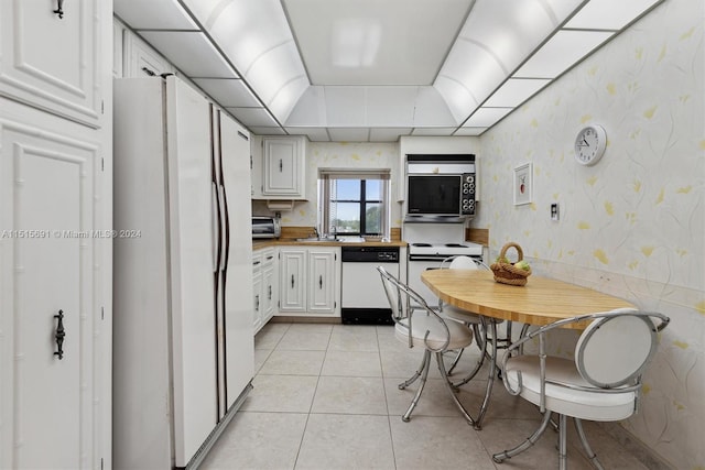 kitchen with white cabinetry, sink, white appliances, and light tile floors