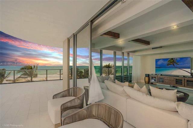 living room with beam ceiling, light tile flooring, and a wall of windows