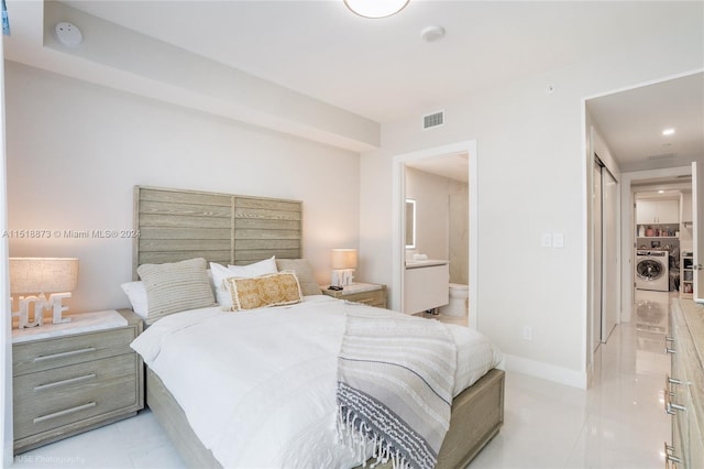 tiled bedroom with ensuite bath and separate washer and dryer