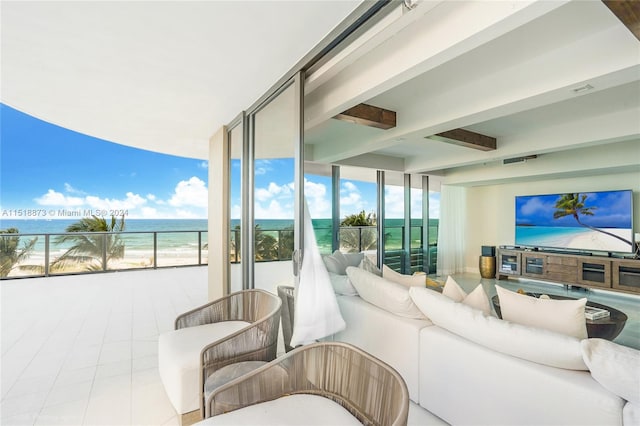 tiled living room with beam ceiling, a water view, and a wall of windows