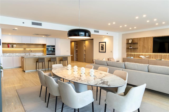 dining area with sink and light wood-type flooring