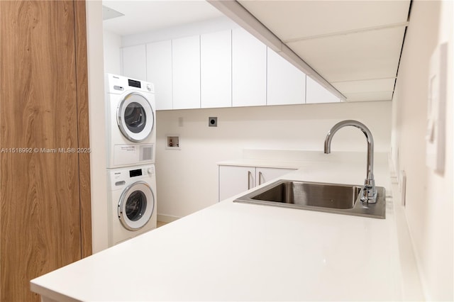 clothes washing area with cabinets, stacked washer and dryer, and sink