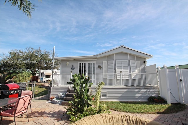 view of front of property with a gate, fence, french doors, and a patio