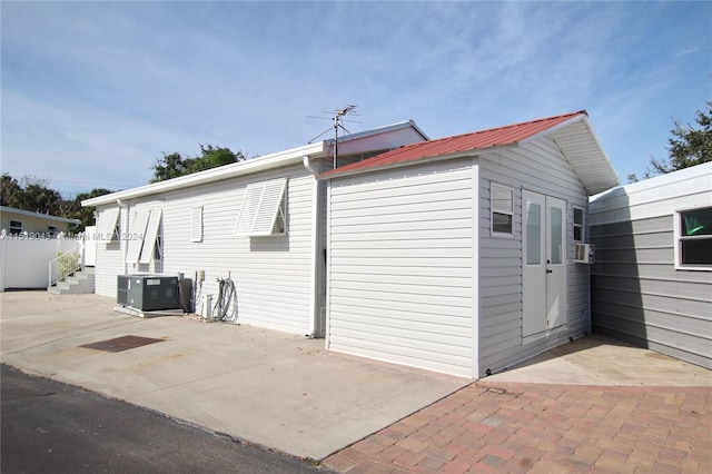 view of side of home with metal roof, a patio, and central AC unit