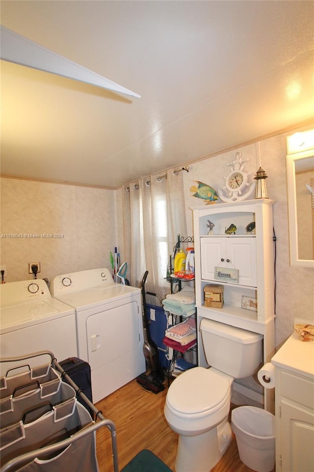 bathroom with toilet, washing machine and dryer, wood finished floors, and vanity