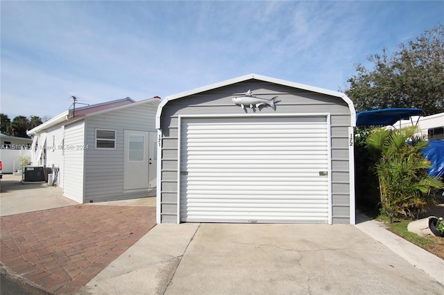 detached garage featuring driveway and cooling unit