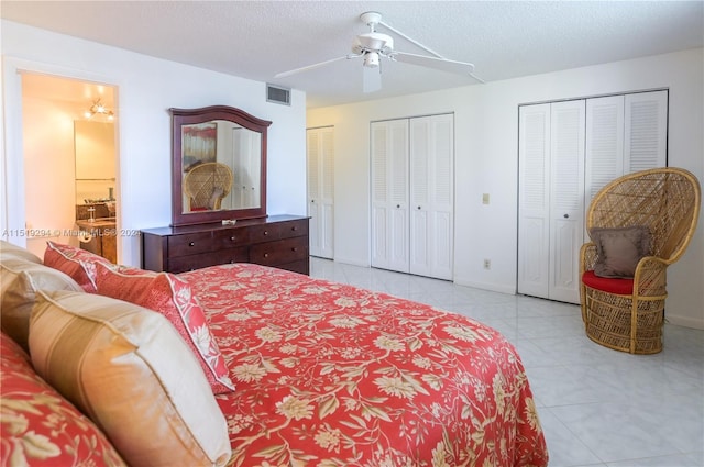 tiled bedroom with ceiling fan, multiple closets, and a textured ceiling