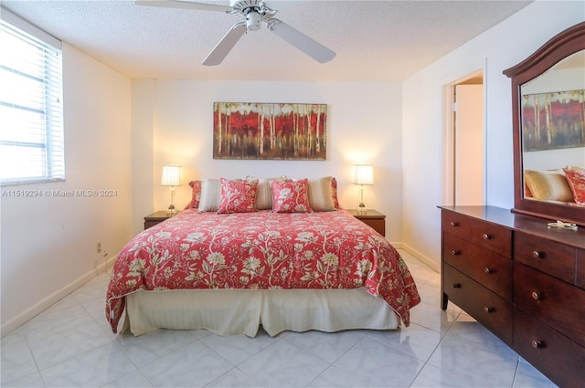 tiled bedroom with ceiling fan and a textured ceiling