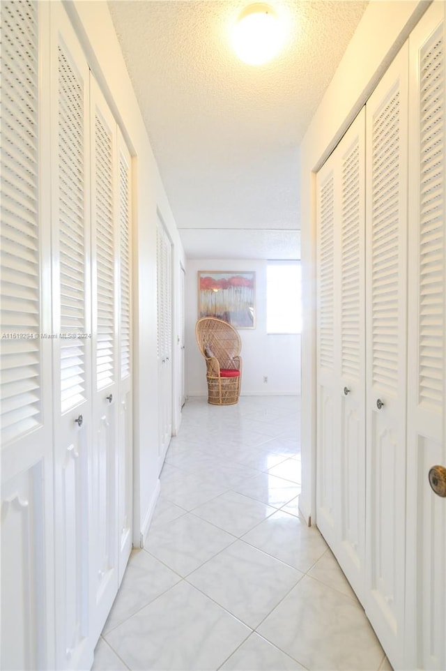 hallway featuring light tile patterned floors and a textured ceiling