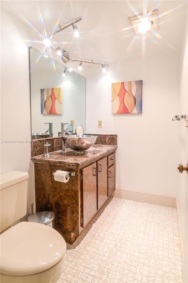 bathroom with tile patterned floors, track lighting, vanity, and toilet