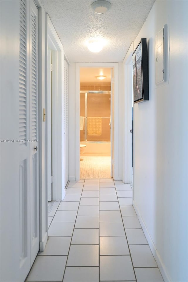 corridor featuring light tile patterned floors and a textured ceiling