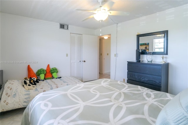 bedroom with ceiling fan, tile patterned flooring, and a closet