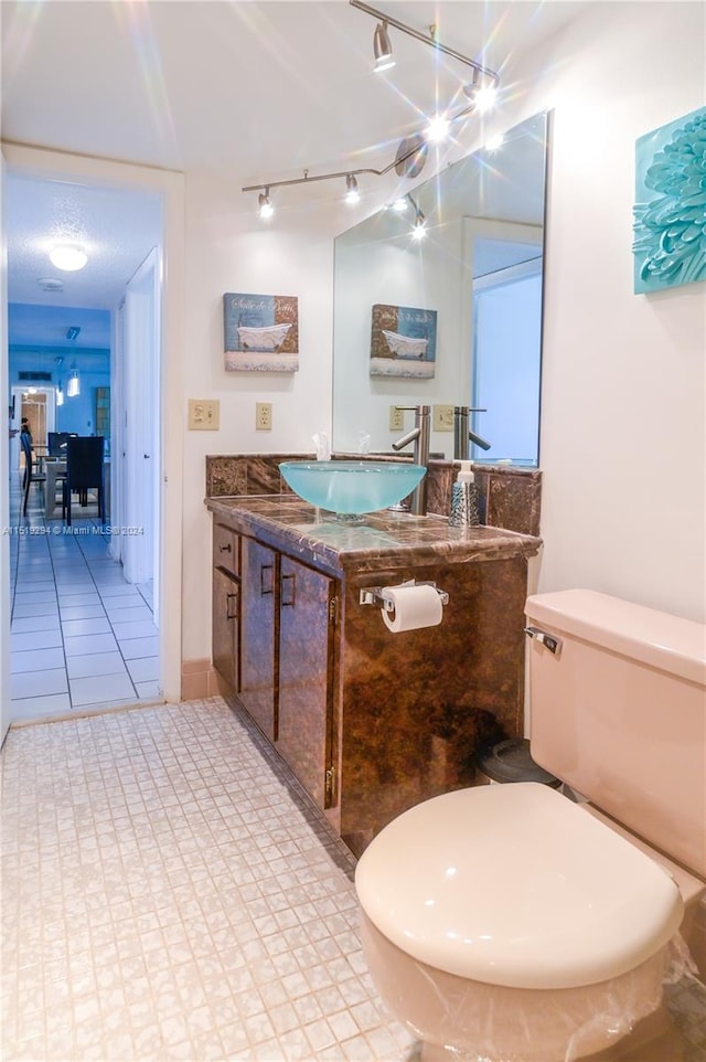 bathroom featuring toilet, rail lighting, vanity, and tile patterned floors