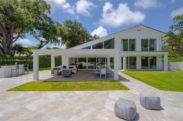 rear view of property featuring a yard, a patio area, and outdoor lounge area