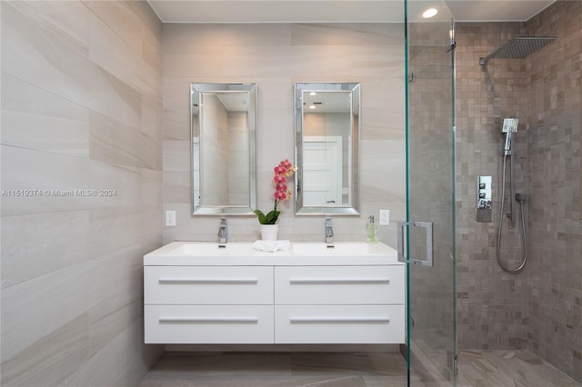 bathroom featuring tile walls, double vanity, and a shower with door