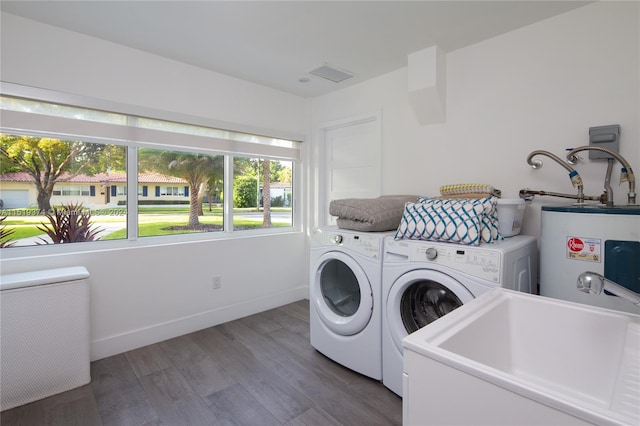 washroom featuring plenty of natural light, water heater, washer and dryer, and dark hardwood / wood-style flooring