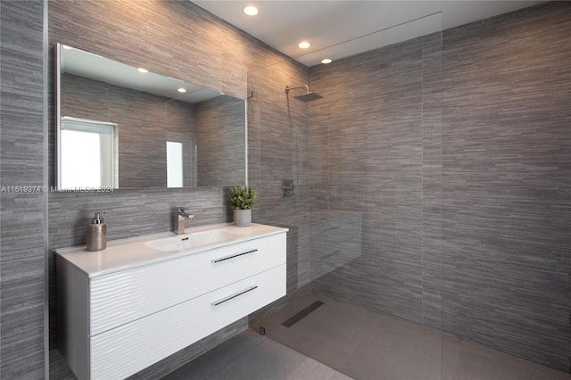 bathroom featuring a tile shower, vanity with extensive cabinet space, and tile walls