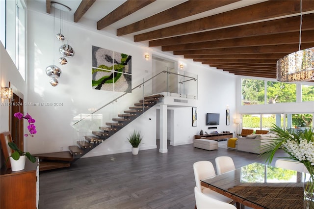 interior space with dark wood-type flooring, a high ceiling, and beam ceiling