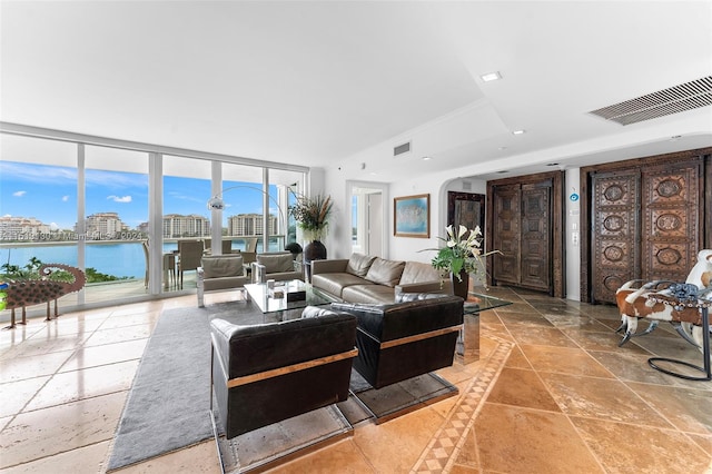 tiled living room with a wall of windows, a tray ceiling, and a water view