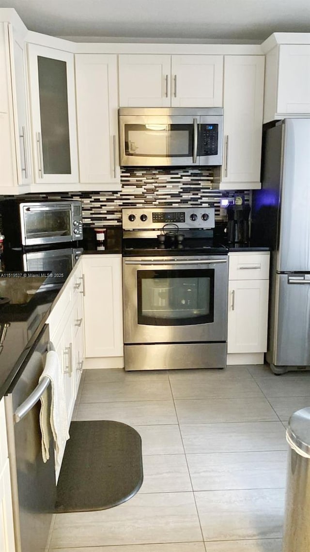 kitchen featuring white cabinets, stainless steel appliances, tasteful backsplash, and light tile patterned floors