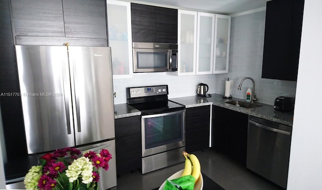 kitchen with light stone counters, backsplash, stainless steel appliances, and sink