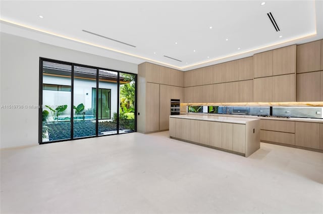 kitchen with a center island, concrete floors, light brown cabinetry, light countertops, and modern cabinets