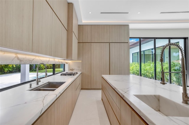 kitchen featuring modern cabinets, light brown cabinets, and a sink