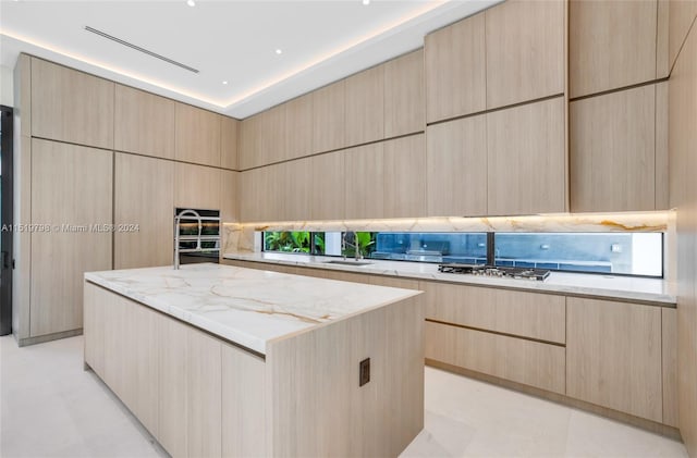 kitchen featuring light stone counters, modern cabinets, gas stovetop, and light brown cabinetry