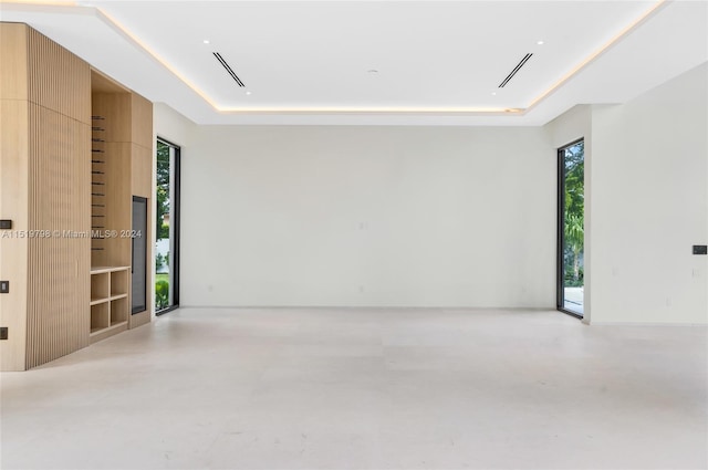 unfurnished room with a tray ceiling, visible vents, and concrete floors