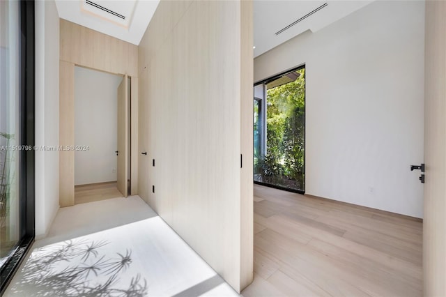 corridor featuring visible vents, a skylight, and light wood-type flooring