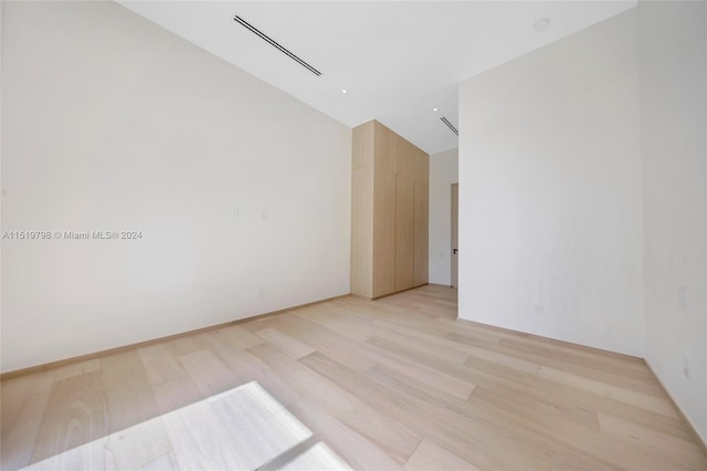 empty room with light wood finished floors and a high ceiling