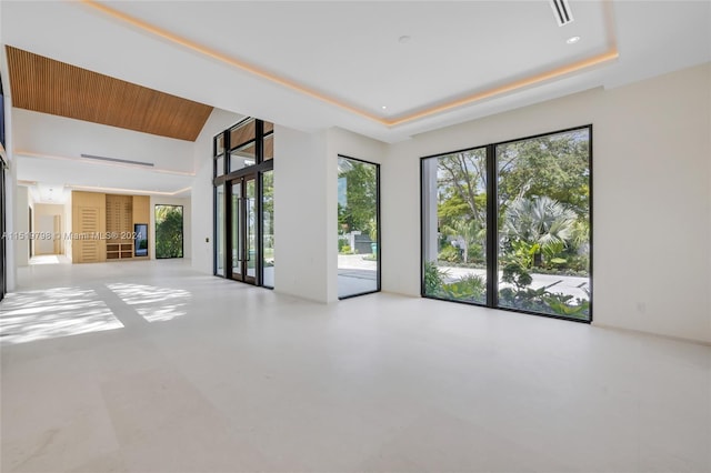 empty room featuring visible vents, wood ceiling, and a raised ceiling