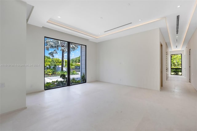 spare room featuring a tray ceiling, recessed lighting, and finished concrete flooring