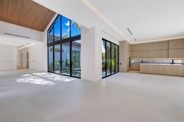 unfurnished living room featuring concrete floors and high vaulted ceiling