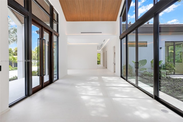 hallway featuring finished concrete flooring, french doors, and a wealth of natural light