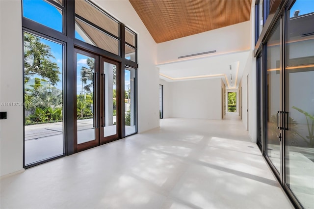 interior space featuring finished concrete floors, plenty of natural light, french doors, and a high ceiling